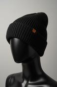 Black knit beanie with a brown logo tag on a white surface KU 7307 image