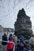 Tourists admiring the Cliffs of Moher from a scenic boat tour, Co Clare, Ireland.