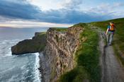 Walker on top of the Cliffs of Moher, County Clare, Ireland.