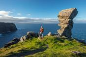 Hiker and rock formation at Hag's Head, Cliffs of Moher, County Clare, Ireland.
