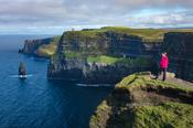 Hiker looking over the Cliffs of Moher from the south, County Clare, Ireland.