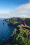 Hiker looking over the Cliffs of Moher from the south, County Clare, Ireland.
