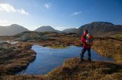 Walker beside a bog pool above Glencorbet, Twelve Bens, Connemara, County Galway, Ireland.