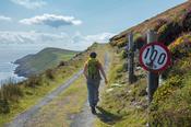 Hiker and quirky speed sign, Dursey Island, Beara Peninsula, County Cork, Ireland.