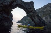 Sea kayaker beneath a rock arch in Skelpoonagh Bay, Glencolmcille, County Donegal, Ireland.