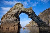 Sea kayaking beneath a natural arch near Sturrall, Glencolmcille, County Donegal, Ireland.