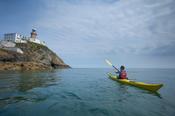 Sea kayaker beneath Baily Lighthouse, Howth Head, County Dublin, Ireland. image