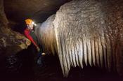 Caver beside a calcite curtain formation, Ballymaclancy Cave, Cong, County Galway, Ireland.