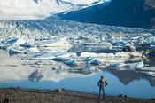 Person beside Fjallsarlon iceberg lagoon, beneath Fjallsjokull glacier, Sudhurland, Iceland.