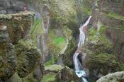Person dwarfed by Fjadrargljufur Canyon, Sudhurland, Iceland.