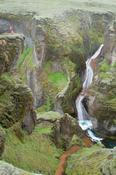 Person dwarfed by Fjadrargljufur Canyon, Sudhurland, Iceland.