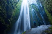 Person in the canyon beneath Gljufurarfossi waterfall, Seljaland, Sudhurland, Iceland.