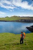 Hiker exploring the Storhofdi peninsula on Heimaey island, Westman Islands, Sudhurland, Iceland.