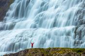 Person dwarfed by Dynjandi waterfall, or Fjallfoss, Westfjords, Iceland.