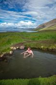 Swimmer taking a dip in Reykjafjardarlaug geothermal pool, beside Arnarfjordur fjord. Westfjords, Iceland.