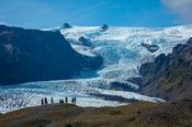 People dwarfed beneath the ice fall of Kviarjokulll glacier. Vatnajokull ice cap, Sudhurland, south east Iceland.