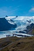 People dwarfed beneath the ice fall of Kviarjokulll glacier. Vatnajokull ice cap, Sudhurland, south east Iceland.