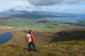 Walker looking across the Dingle Peninsula from Eagle Mountain, County Kerry, Ireland.