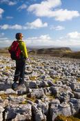Walker on limestone pavement, Keelogyboy Mountain, Co Leitrim, Ireland.