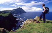 Walker admiring the seacliffs of north Clare Island, Co Mayo, Ireland.