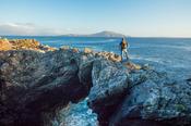 Hiker standing on a sea arch, Dooega Head, Achill Island, Co Mayo, Ireland. image