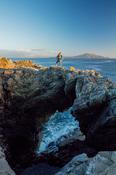 Hiker standing on a sea arch, Dooega Head, Achill Island, Co Mayo, Ireland.