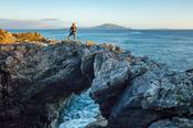 Hiker standing on a sea arch, Dooega Head, Achill Island, Co Mayo, Ireland.