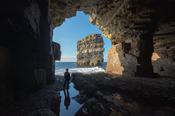 Person viewing Dun Briste sea stack from a cave beneath Downpatrick Head. County Mayo, Ireland. image