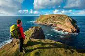 Coastal walker looking towards Kid Island, on the Children of Lir coast walk. Carrowteige, County Mayo, Ireland.