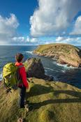 Coastal walker looking towards Kid Island, on the Children of Lir coast walk. Carrowteige, County Mayo, Ireland.