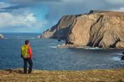 Coastal walker admiring the 260m sea cliffs of Benwee Head. Carrowteige, County Mayo, Ireland.