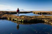 Walker and tarn on the summit ridge of Slieve Carr, Nephin Beg Mountains, Co Mayo, Ireland.