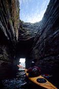 Sea kayaker in the cave beneath Downpatrick Head, Co Mayo, Ireland.