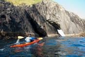 Sea kayaker beside a rock arch, Stags of Broadhaven, Portacloy, Co Mayo, Ireland.