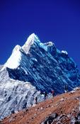 Trekkers beneath Kimshun (6745m), Langtang Valley, Nepal.