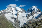 Hiker beneath Piz Bernina and Piz Rosbeg, Fuorcla Surlej, Berniner Alps, Graubunden, Switzerland.