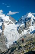 Hiker beneath Piz Bernina and Piz Rosbeg, Fuorcla Surlej, Berniner Alps, Graubunden, Switzerland.