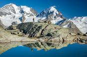 Reflection of hiker beneath Piz Bernina and Piz Rosbeg, Fuorcla Surlej, Berniner Alps, Graubunden, Switzerland.