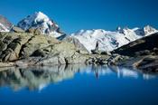 Reflection of hiker beneath Piz Rosbeg, Fuorcla Surlej, Berniner Alps, Graubunden, Switzerland.