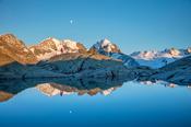 Reflection of hiker beneath Piz Bernina and Piz Rosbeg, Fuorcla Surlej, Berniner Alps, Graubunden, Switzerland.