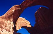 Person silhouetted beneath Double Arch, Arches National Park, Utah, USA. image