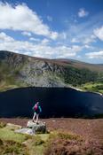 Walker admiring the view over Lough Tay, Wicklow Mountains, Co Wicklow, Ireland.