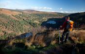 Walker looking over Glendalough from The Spinc, Wicklow Mountains National Park, County Wicklow, Ireland.