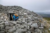 Walker and neolithic tomb at the summit of Seefin (621m), Wicklow Mountains, County Wicklow, Ireland.