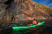 Sea kayaker beside a blow-hole rainbow, Arranmore Island, County Donegal, Ireland.