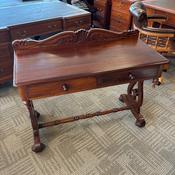Antique carved mahogany writing table with a scrolled stretcher image