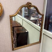 An elegant decorative wall mirror, ornate floral and ribbon-style crest